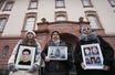 Samaa Mahmoud, Mariam Alhallak et Yasmen Almashan tiennent les portraits de leurs proches tués en Syrie, devant le tribunal de Coblence, le 13 janvier 2022.