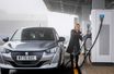 Une femme recharge sa Peugeot électrique.