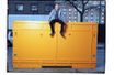 Jeff Koons assis sur une boîte de transport de l'une de ses oeuvres devant son atelier newyorkais.
