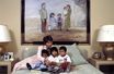 Marina Picasso avec ses trois enfants vietnamiens, dans une chambre de sa villa "La Californie", devant un tableau de son grand-père Pablo Picasso. 1992.