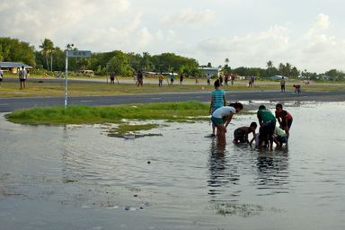 Des enfants jouent avec les trous d’infiltration par lesquels les marées inondent Funafuti, l’île capitale