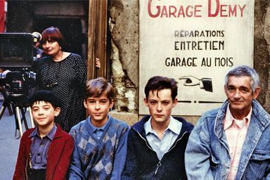 <br />
Demy devant le garage familial sur le tournage de « Jacquot de Nantes », avec à ses côtés les acteurs qui interprètentsonrôle à différents  âgeset Agnès en arrière-plan.