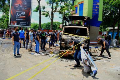 La police mène une enquête à côté d'un véhicule incendié à l'extérieur du stade Kanjuruhan à Malang, dans l'est de Java, le 2 octobre 2022.