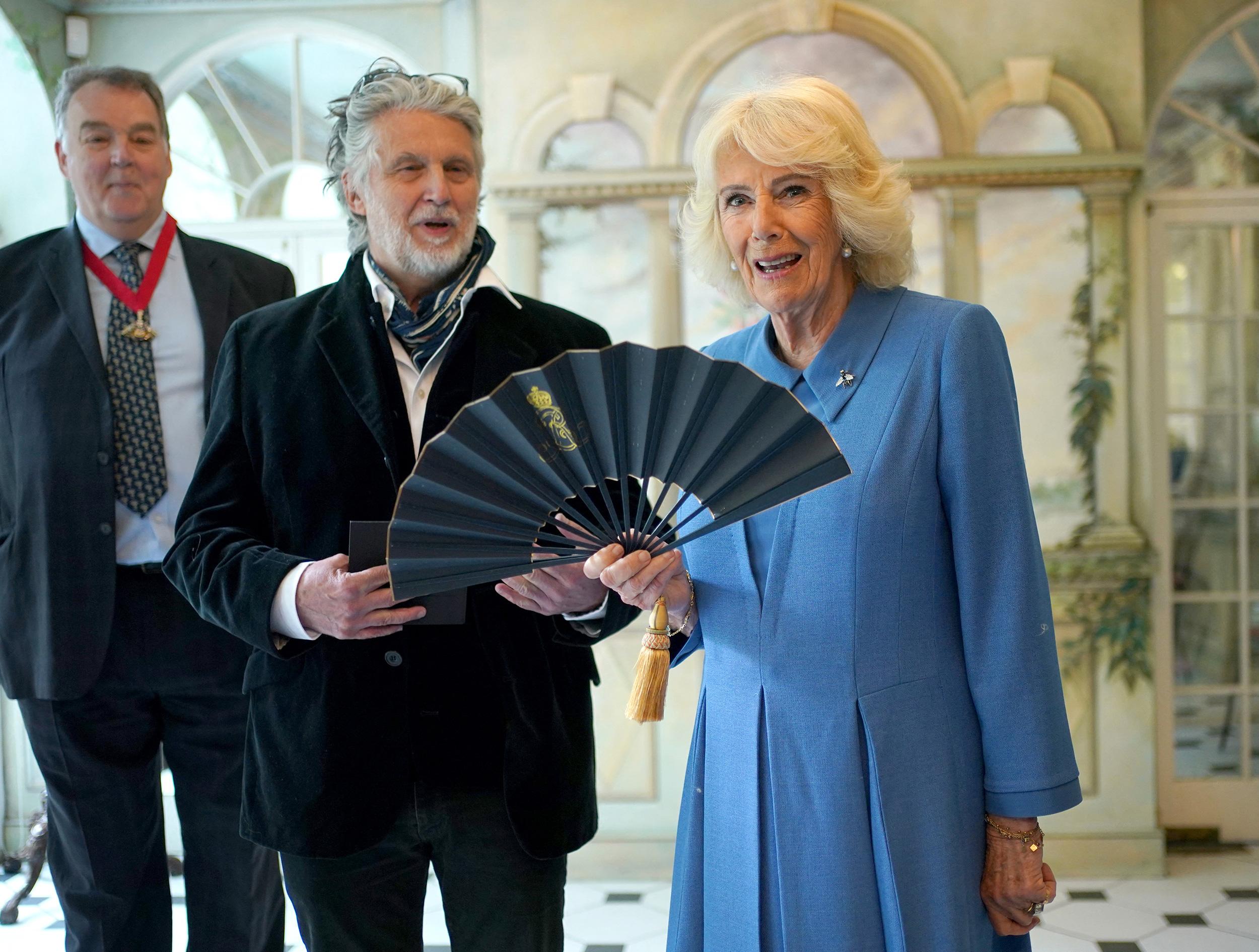Radieuse dans une robe assortie à ses yeux, la reine Camilla reçoit l’éventail de son portrait de couronnement